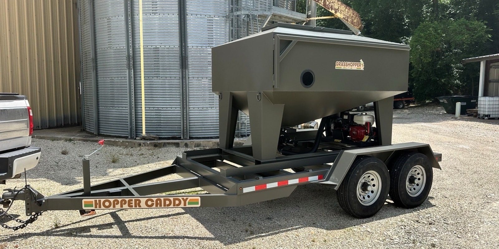 Grasshopper 130 seed tender loaded on a Hopper Caddy trailer beside a grain bin